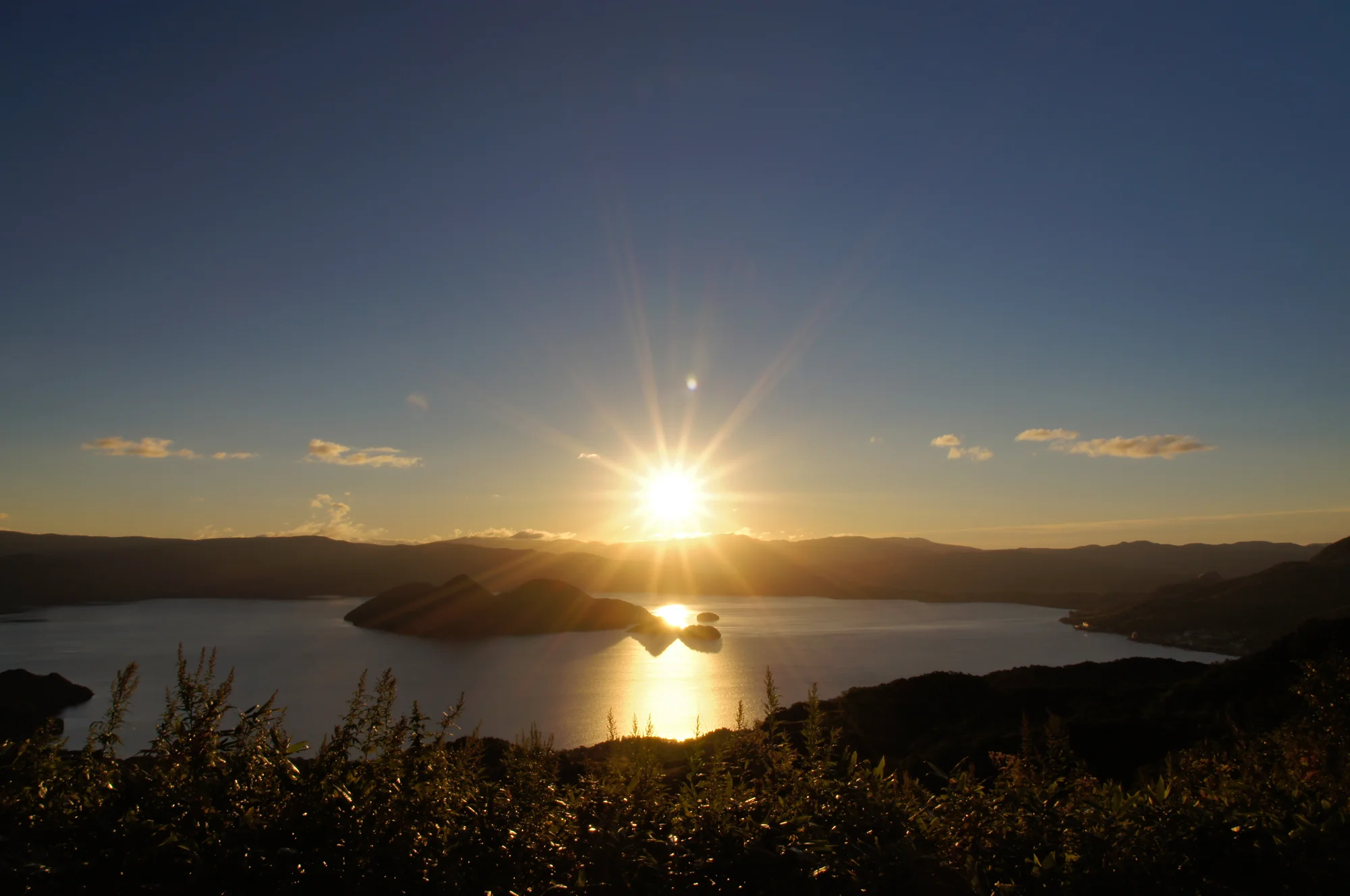 洞爺湖太陽宮度假村外觀，大型建築面向湖面，前方有庭園與足湯設施