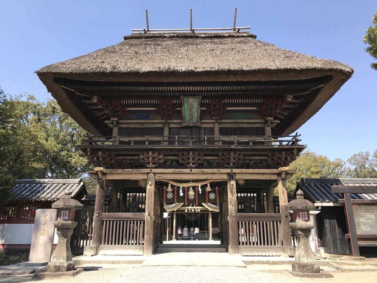 人吉青井阿蘇神社的茅葺樓門,藍天下厚重茅草屋頂醒目。