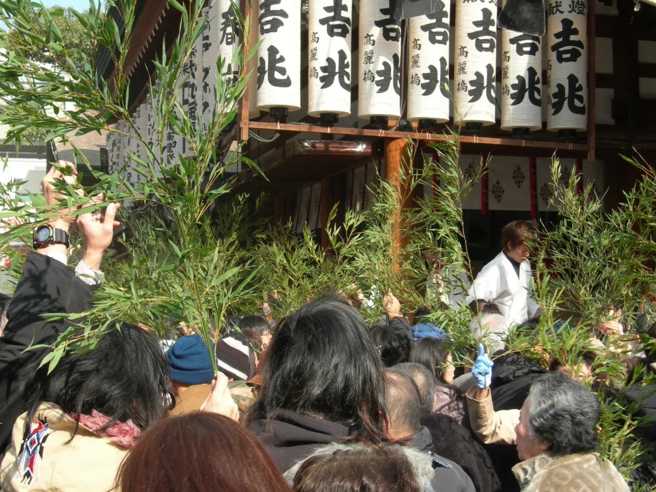 西宮神社境內傳統建築前，遊客駐足觀賞，白色紙燈籠與青綠植物環繞