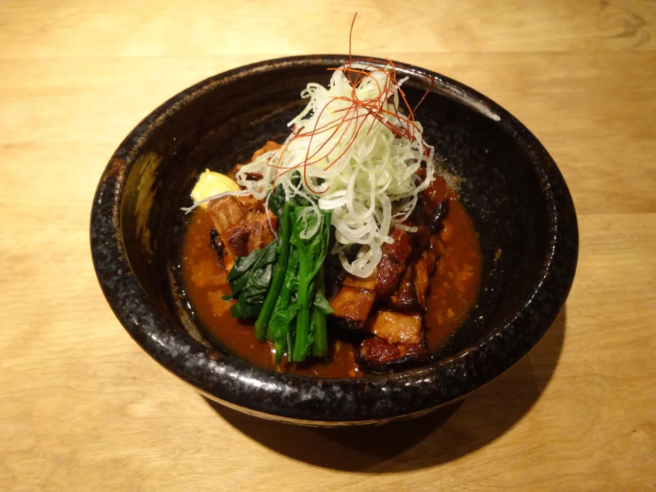 黑霧島芋燒酎與鹿兒島黑豚肉盤，木製餐具搭配，溫橙色燈光映照。