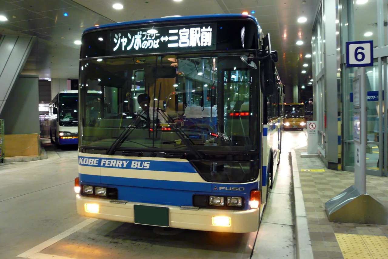 神戶三宮巴士總站，藍白色高速巴士停泊室內月台，夜間LED燈照亮車身，往淡路島班次最密集。