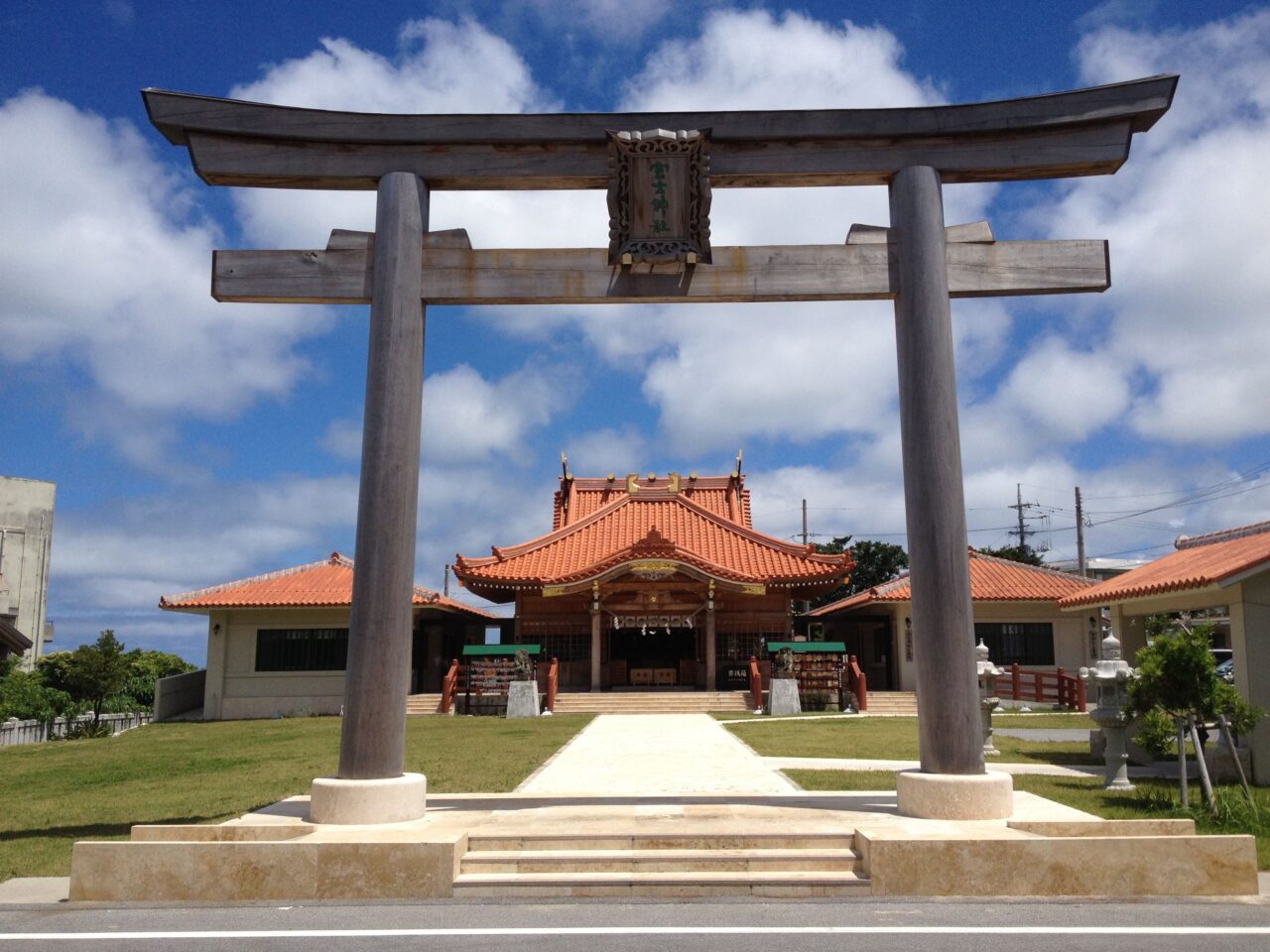 宮古神社的木造鳥居與紅瓦社殿,兩側石獅與紅色欄杆,晴朗藍天。