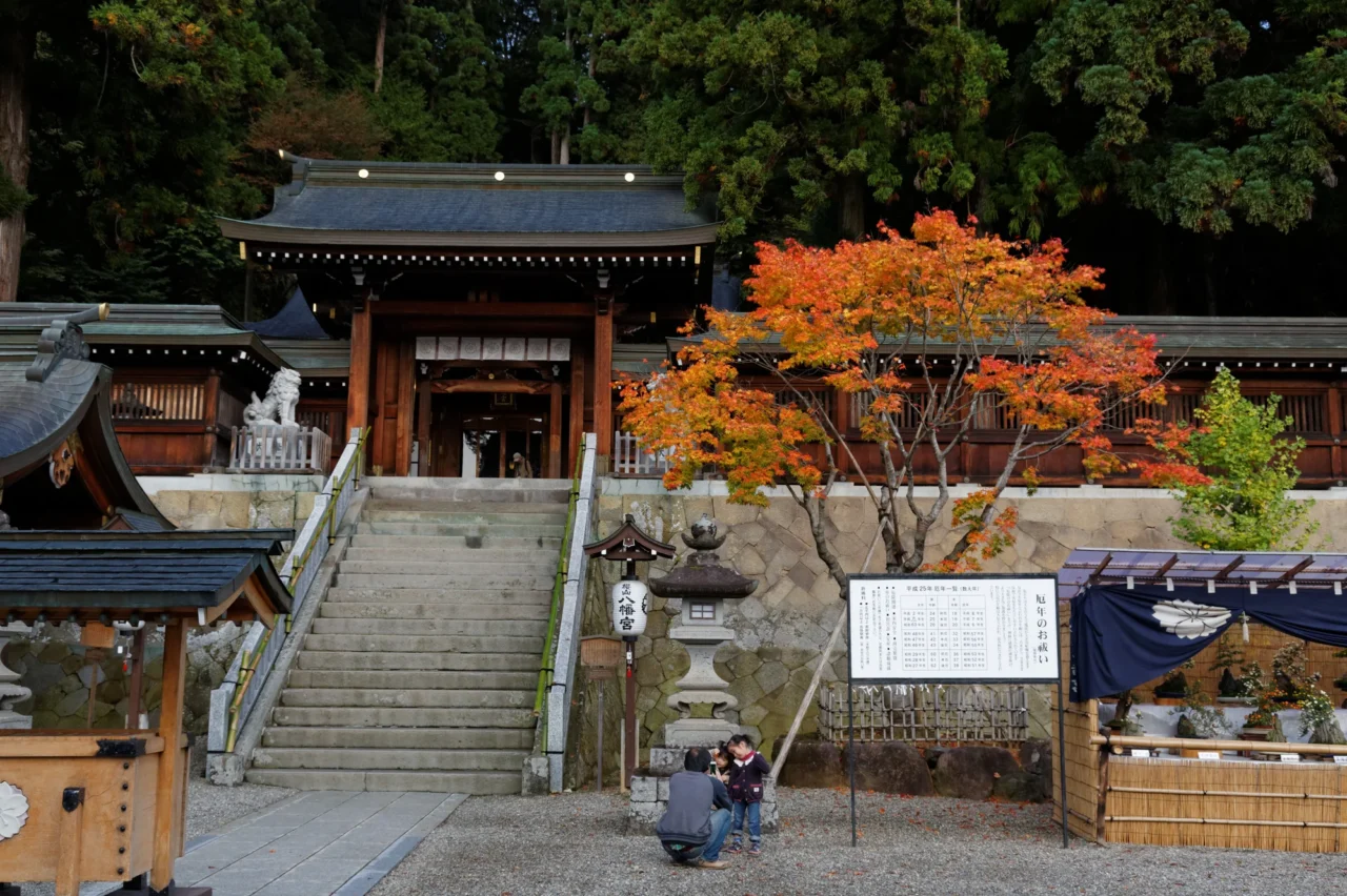 櫻山八幡宮石階前秋季紅楓映照，白色院落告示牌依稀可見，晴朗天候古剎莊嚴。