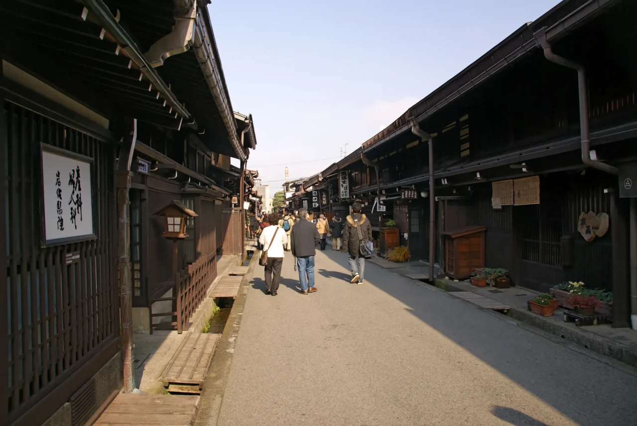 宮川朝市木造傳統商店街，沙土路面兩側排列盆栽，背景古塔映照晴朗上午光線。