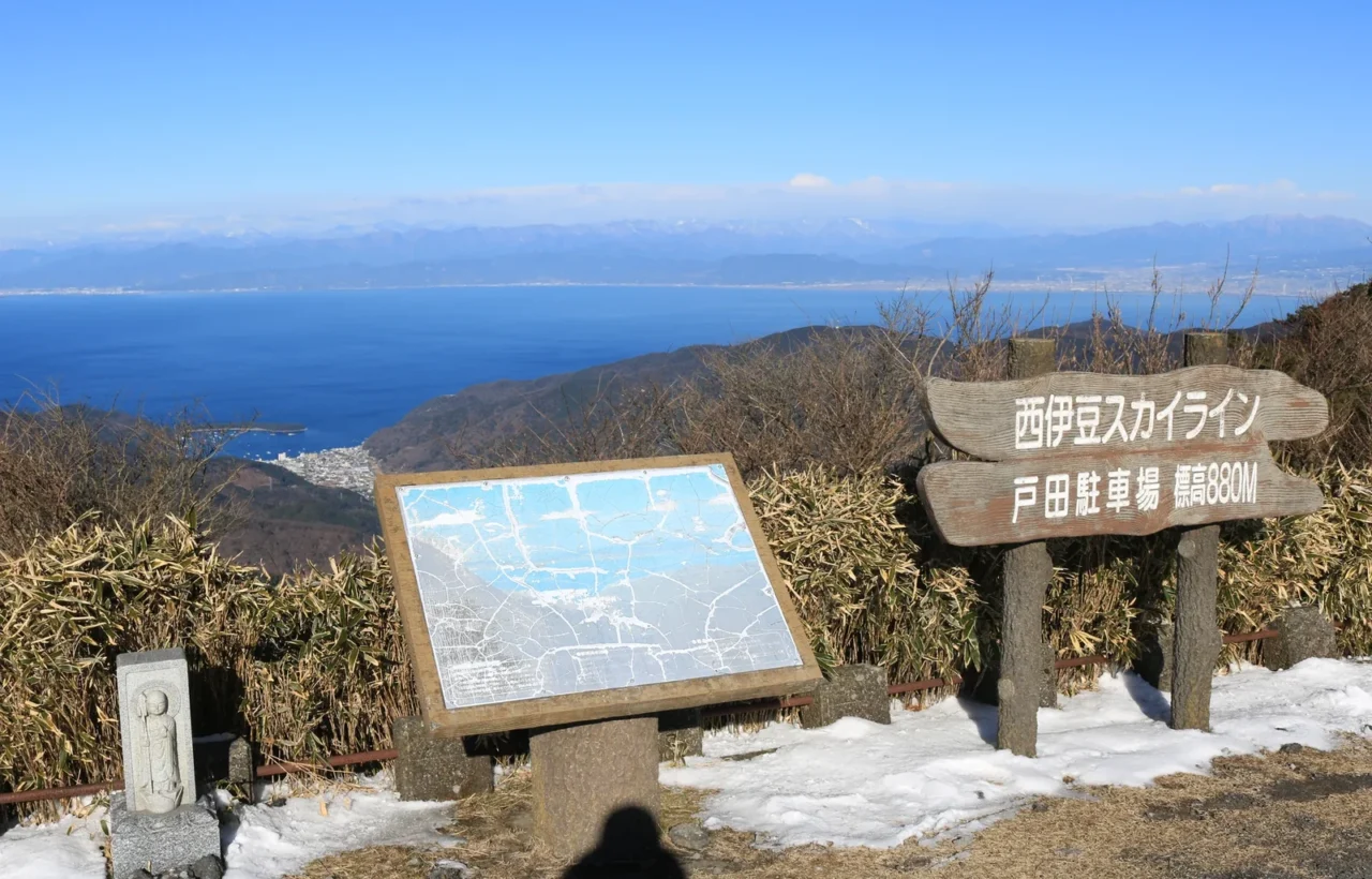 西伊豆天景線觀景台木製標誌與地圖看板豎立,背景相模灣與白雪覆蓋遠山。